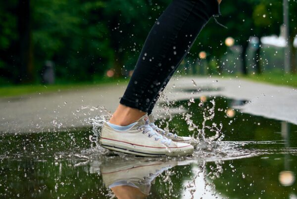 a girl jumping on a small puddle of water
