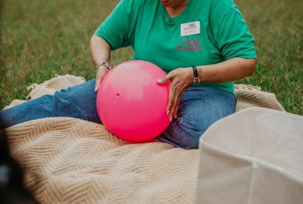 caretake with a large pink ball playing with kids