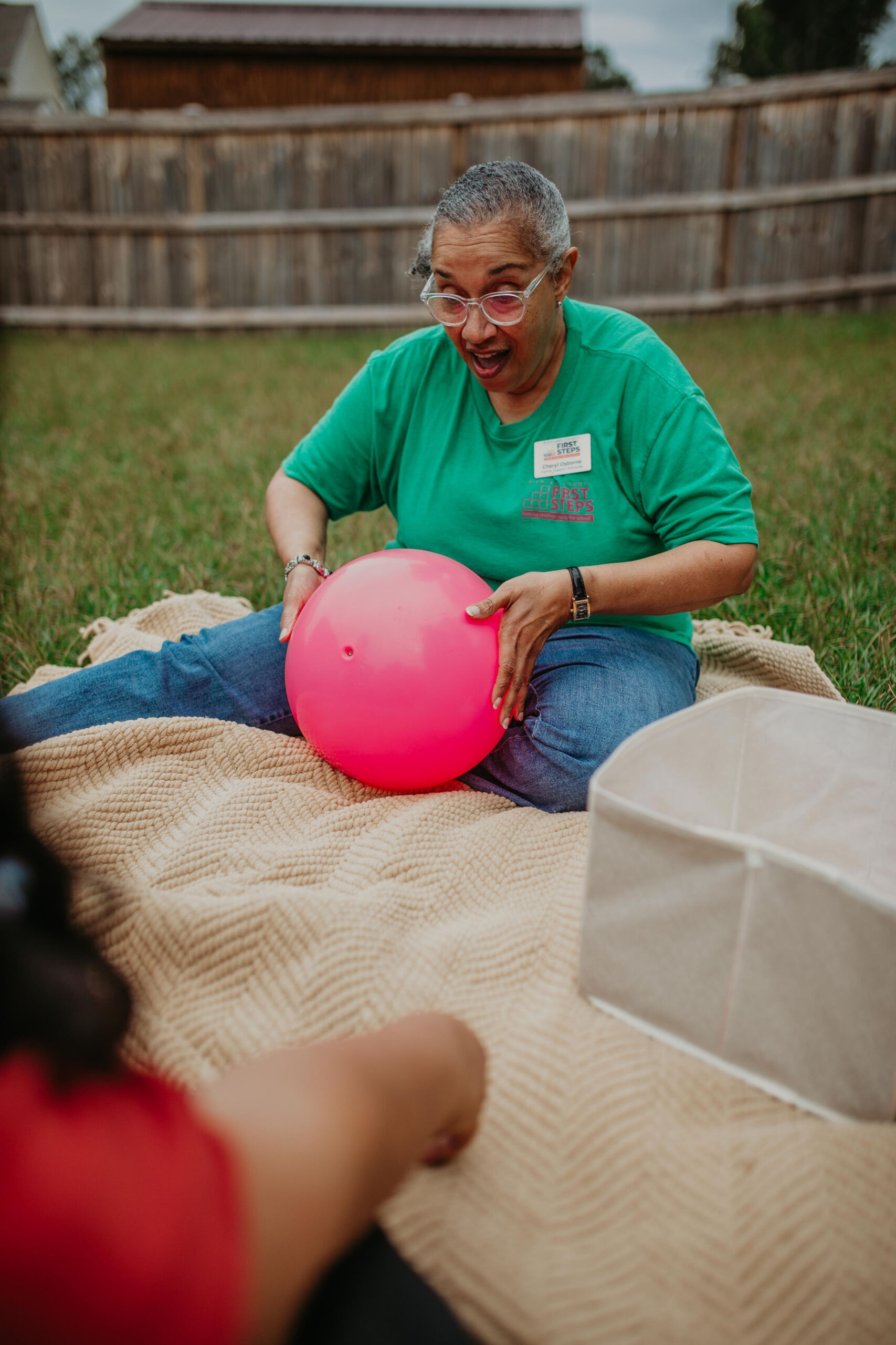 caretake with a large pink ball playing with kids